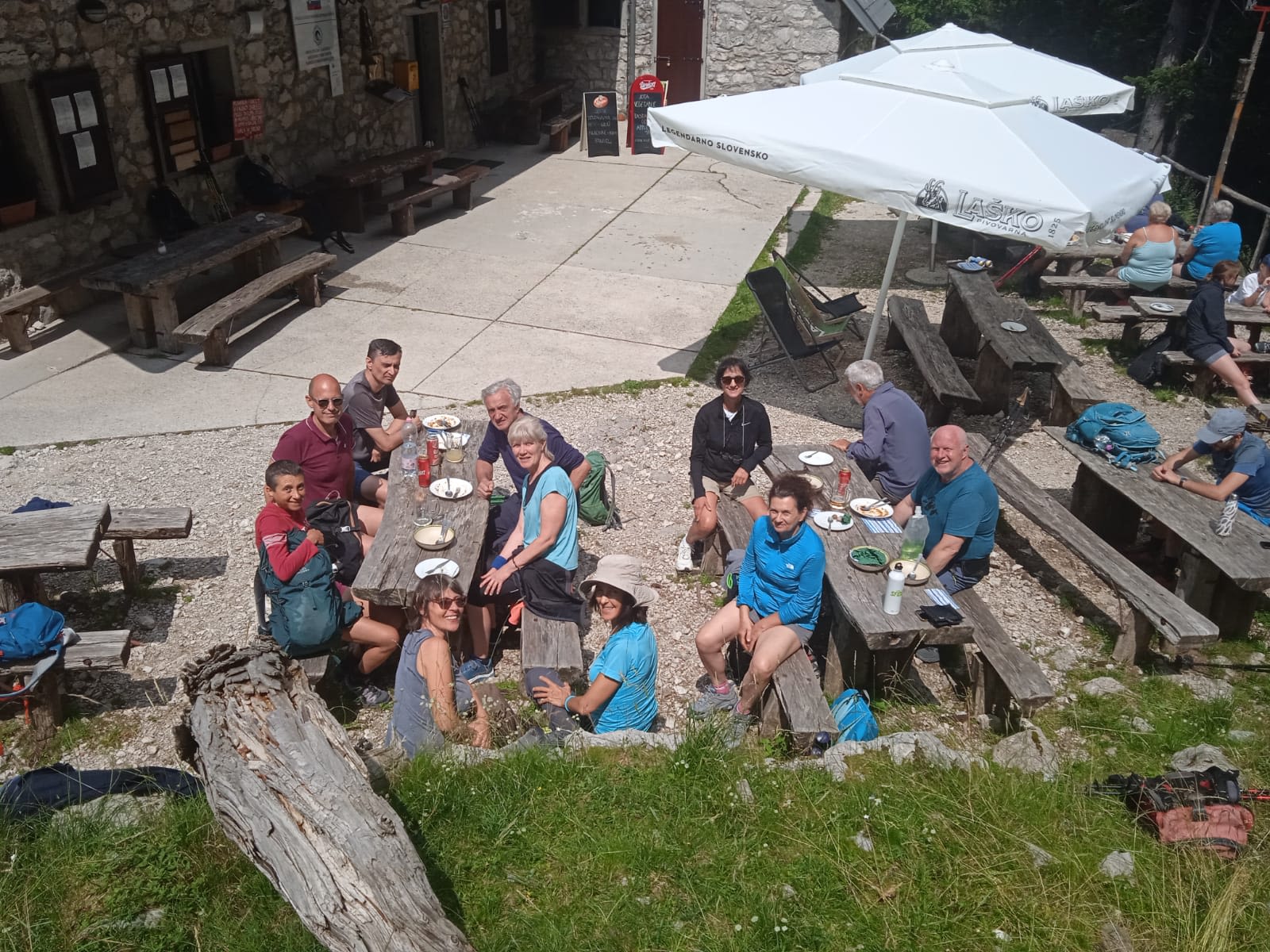 Gruppo di turisti seduti all'aperto in una baita di montagna, rilassandosi nel Parco del Triglav, Slovenia.